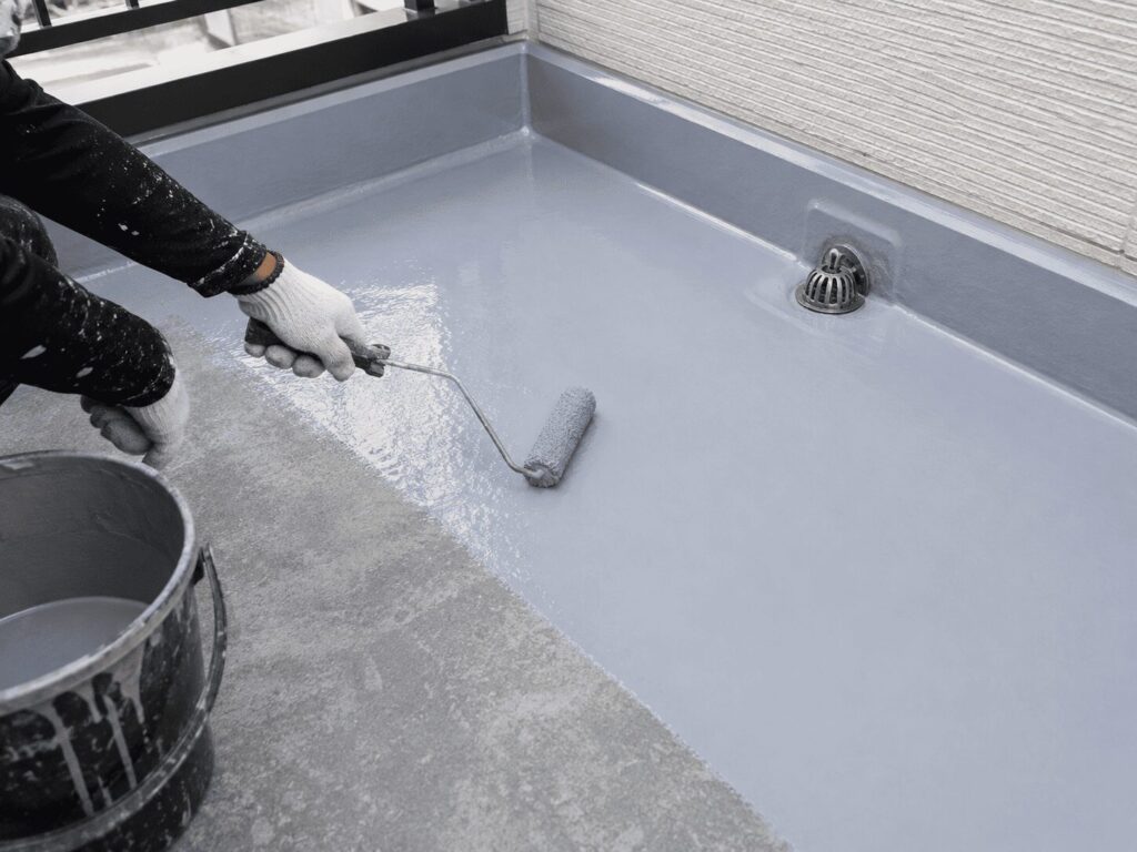 ベランダの防水工事を行う塗装職人