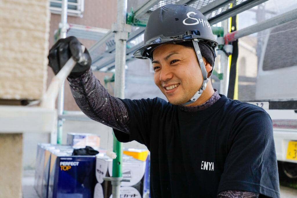 笑顔で塗装工事を行う職人の写真
